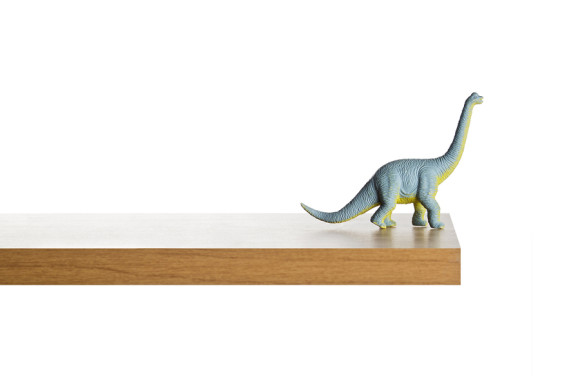 Dinosaur figurine placed on a ledge against a white background ** Note: Slight blurriness, best at smaller sizes