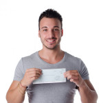 Happy smiling young man with check in hands looking at camera