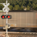 Motion blurred locomotive at railroad crossing with signal box