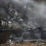 In this Nov. 10, 2015, file photo, a charred car and aircraft debris smolder where a small business jet crashed into an apartment building in Akron, Ohio. The National Transportation Safety Board is scheduled to meet in Washington on Tuesday, Oct. 18, 2016, to decide the probable cause of a corporate jet crash that killed the two pilots and seven passengers, and occurred within two miles of Akron Fulton International Airport while descending for landing. No one on the ground was injured. (Ed Suba Jr./Akron Beacon Journal via AP, File)