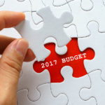 Hand holding a piece of white puzzle with word 2017 BUDGET.