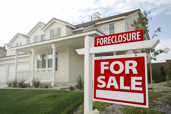 Foreclosure Home For Sale Sign and House with Dramatic Sky Background.
