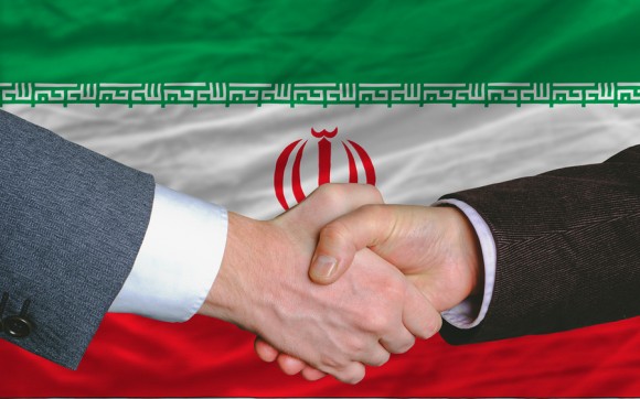 businessmen handshake after good deal in front of iran flag