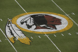 In this photo taken Aug. 7, 2014, the Washington Redskins logo is seen on the field before an NFL football preseason game against the New England Patriots in Landover, Md. Lawyers for the Washington Redskins are telling a judge that the team's free-speech rights are being infringed by a federal panel's decision to cancel the team's trademarks for being disparaging to Native Americans. (AP Photo/Alex Brandon)