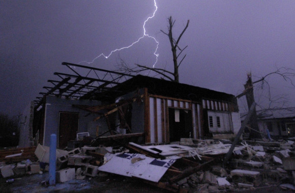 Lightning illuminates a house after a tornado touched down in Jefferson County, Ala., damaging several houses, Friday, Dec. 25, 2015, in Birmingham, Ala. A Christmastime wave of severe weather continued Friday. (AP Photo/Butch Dill)