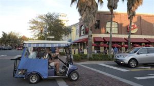 Residents ride their golf cart on a street at the Lake Sumter Landing Market Square in The Villages, Florida. Growing numbers of seniors in some areas are using golf carts and mixing with traffic on public roads, which worries safety experts. © The Associated Press 