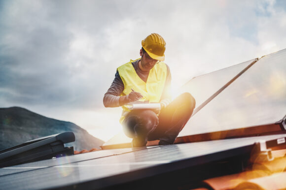 Man works on renewable energy with solar panel for electricity and hot water