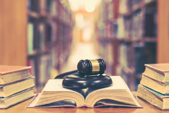 Old book in library with judge gavel on open law textbook in cou