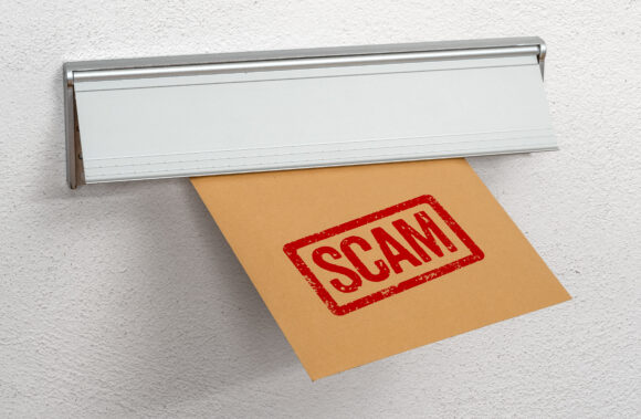 A letter stamped Scam in a mail slot