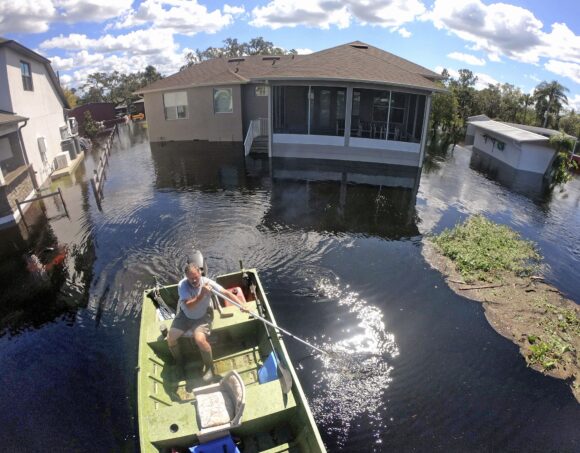 Resident Mike Kelley navigates flooded streets in the Mullet Lake neighborhood, Wednesday, Oct. 5, 2022, in Geneva, Fla., as floodwaters from Lake Harney and the St. Johns River continue to rise following historic levels of rainfall from Hurricane Ian last week. (Joe Burbank/Orlando Sentinel)