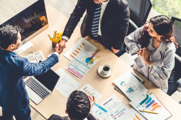 Group business people handshake at meeting table in office together with confident shot from top view . Young businessman and businesswoman workers express agreement of investment deal.