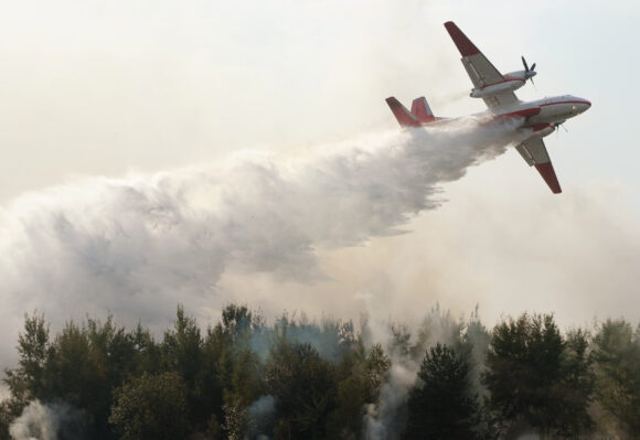 plane drops fire retardant and water on a forest fire