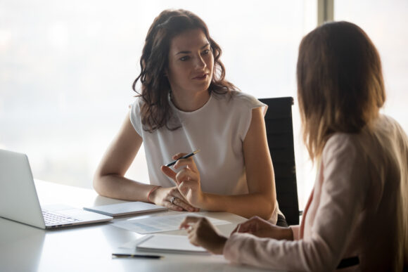 Two diverse serious businesswomen discussing business project working together in office, serious female advisor and client talking at meeting, focused executive colleagues brainstorm sharing ideas