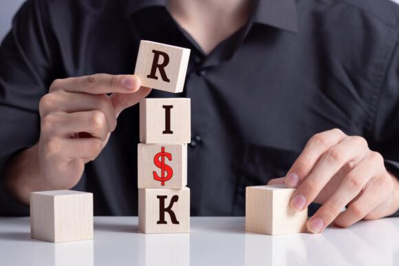 a man's hand puts wooden cubes and makes up the word RISK, risk insurance, Risk taking, risk management concept