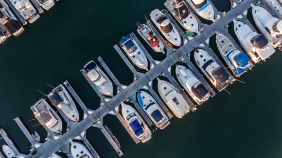 Aerial view of boats in their slips. The location where these boat docks are located is Huntington Harbor. Huntington Harbor is in Orange County, California.