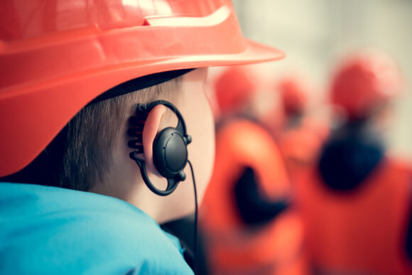 A boy in safety helmet with earphone in his ear. Young engineer concept.