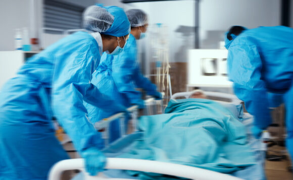Women, man and hospital bed in motion blur of emergency surgery, healthcare wellness or risk condition operation. Doctors, nurses and medical workers with patient in busy er, theatre room or teamwork.