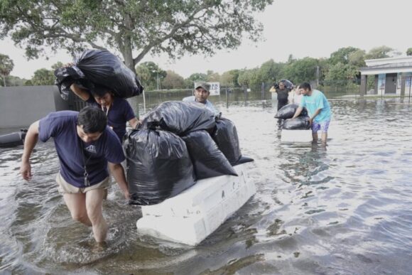 People try and save valuables, wading through high flood waters in a Fort Lauderdale, Fla., neighborhood on Thursday, April 13, 2023. South Florida is keeping a wary eye on a forecast that calls for rain a day after nearly a foot fell in a matter of hours. The rains caused widespread flooding, closed the Fort Lauderdale airport and turned thoroughfares into rivers. (Joe Cavaretta/South Florida Sun-Sentinel via AP)