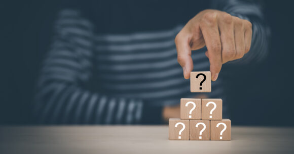 Hand hold Wooden cube block in question mark mean what on cement table background, column of wooden blocks with question sign mark. copy space,FAQ frequently asked questions, Answer, Information