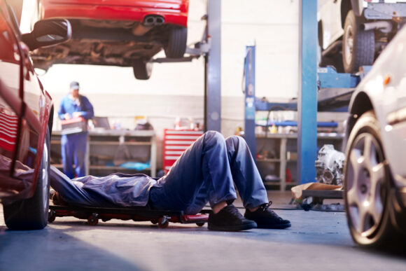 Mechanic under car in auto repair shop