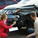 Man reporting and insurance agent filling claim form near broken car outdoors