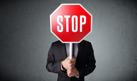 Businessman standing and holding a stop sign in front of his head