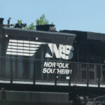 Atlanta, USA - April 20, 2018: Norfolk Southern locomotive cargo freight train with cars passing on railroad tracks in Georgia downtown midtown city in summer