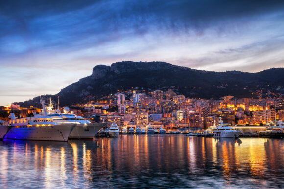 Principality of Monaco picturesque evening skyline, city lights with reflection in Mediterranean Sea