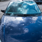 hail damage to car. damaged hood and windshield