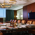 Part of spacious boardroom for working meetings of directors or lawyers with long table surrounded by several leather armchairs