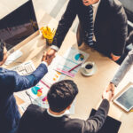 Group business people handshake at meeting table in office together with confident shot from top view . Young businessman and businesswoman workers express agreement of investment deal.