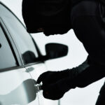 Man, car and steal with theft tool, picking lock and illicit behaviour or automobile jacking. Criminal, makeshift key and hooded offender or disabling vehicle alarm, parking lot and illegal burglary.