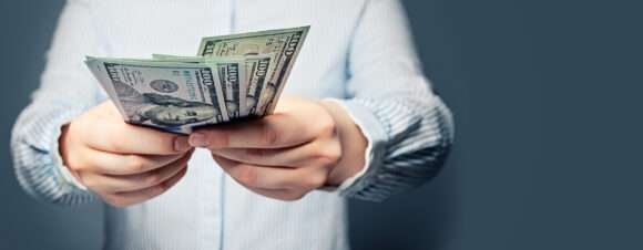 Hands giving money US dollars on blue background