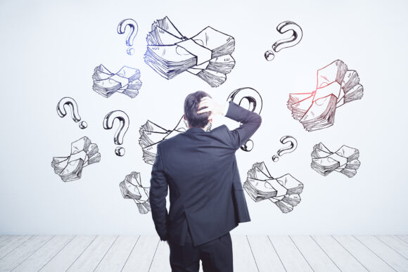 Earning money and business idea concept with pensive businessman looking at white wall with handwritten sketch of money packs and question marks