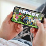 Roblox mobile iOS game on iPhone 15 smartphone screen in female hands during mobile gameplay. Mobile gaming and entertainment on portable device