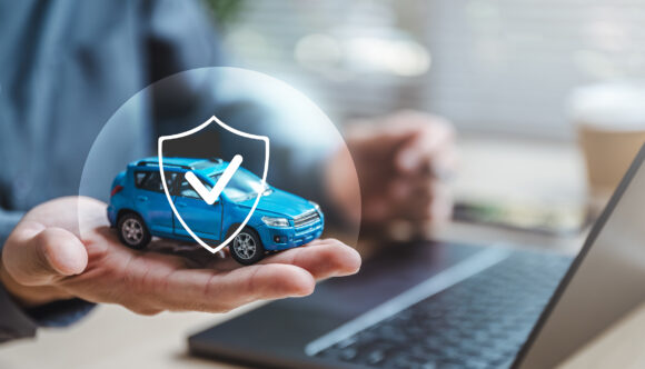 Car insurance protect safe transport. Safety trust. Protection secure assurance. A person is holding a blue toy car with a sticker that says protected on it. The car is placed on a laptop computer.