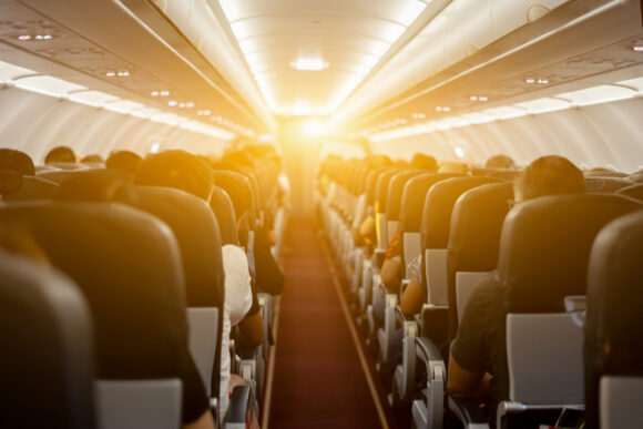 Air hostesses and passenger seat, Interior of airplane with passengers sitting on seats and welcomer stewardess walking the aisle in background. Travel by plane concept,vintage color,selective focus