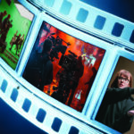 Curving illuminated film strip featuring scenes from movie production, including a film set, camera crew, and director holding a clapperboard against a dark blue background.