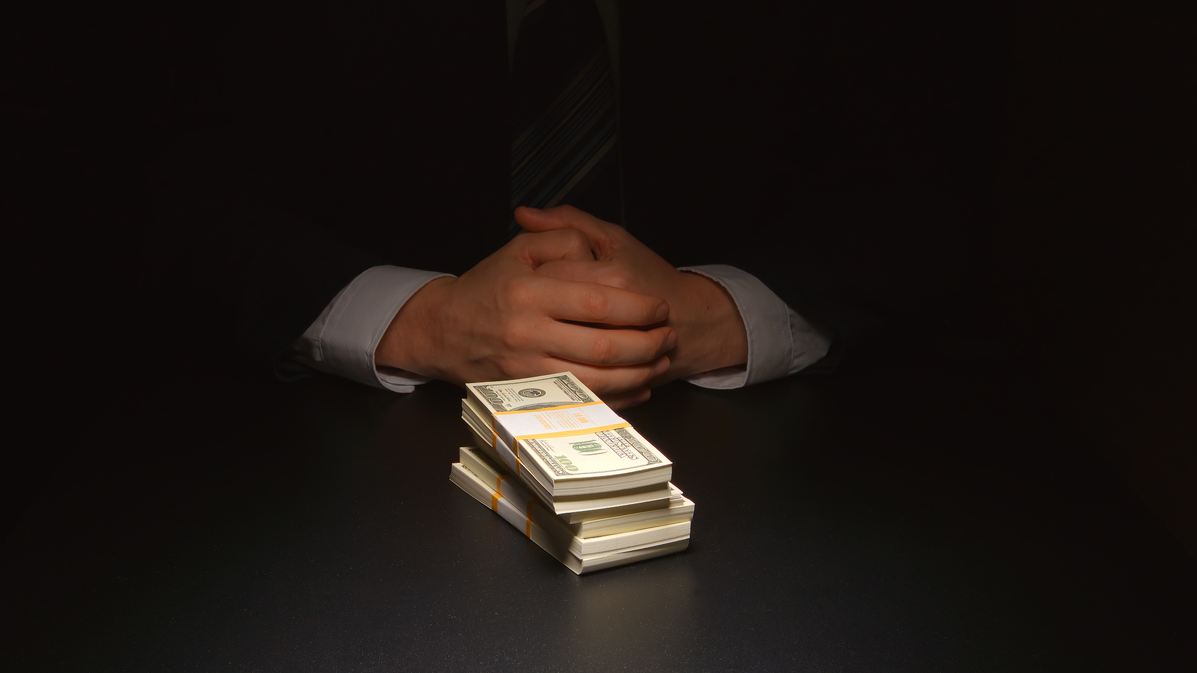 BRIBE: Businessman sits near a heap money on a table