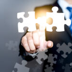 Mergers and acquisition concept with consultant touching icons of puzzle pieces