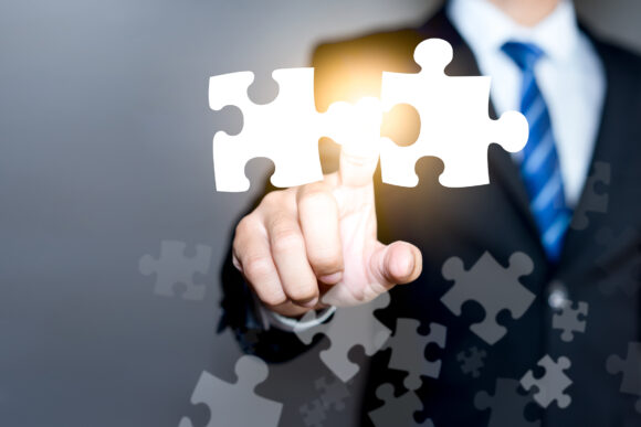 Mergers and acquisition concept with consultant touching icons of puzzle pieces