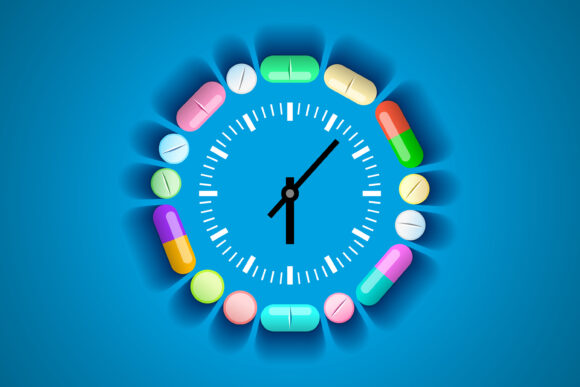 Clock and pills and tablets around it. Concept of taking medications by time, treatment schedule. Healthcare and medical concept