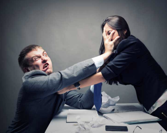 Man aggressively grabbing a coworker across a desk, depicting workplace violence and conflict