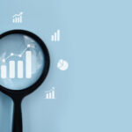 Magnifying glass analyzing business growth charts and data icons