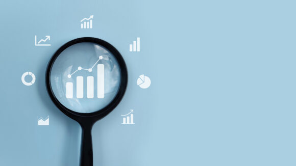 Magnifying glass analyzing business growth charts and data icons