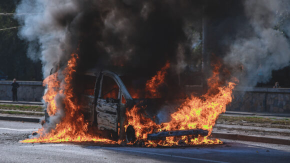 the car is standing on the road and is on fire