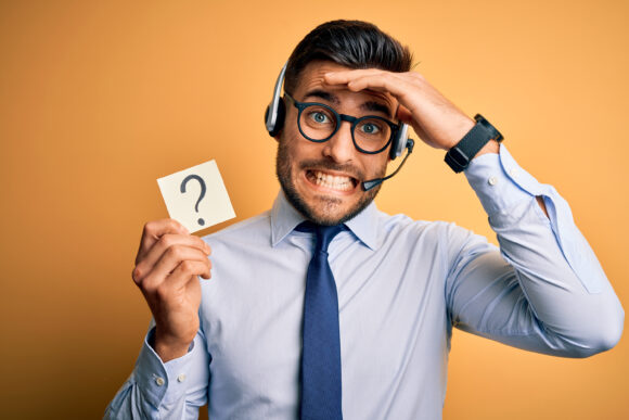 Business operator man with customer service headset from call center showing question mark stressed with hand on head, shocked with shame and surprise face, angry and frustrated. Fear and upset for mistake.