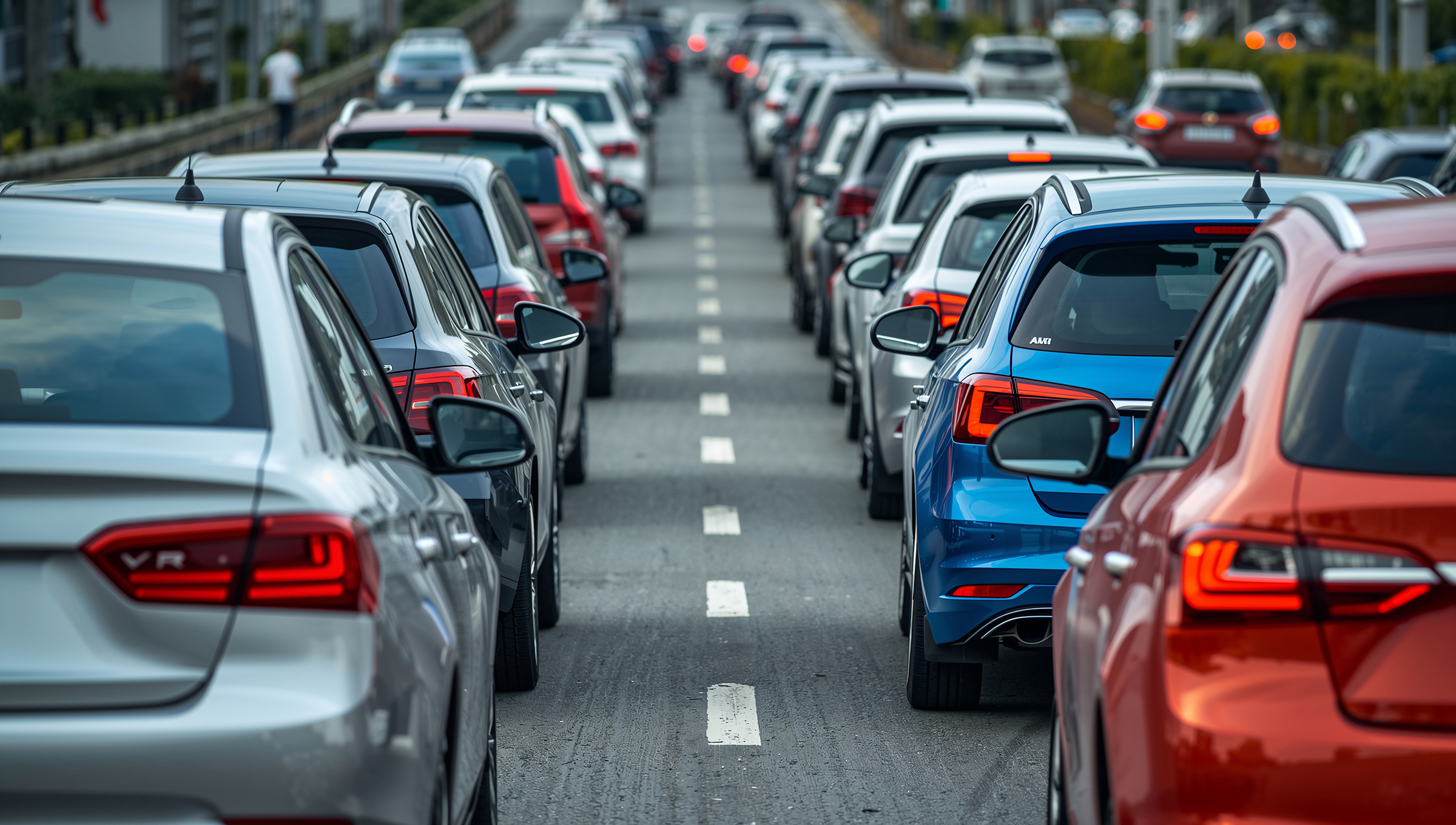 A long queue of vehicles stuck in congested traffic on a multi-lane road during daytime hours, AI generated image