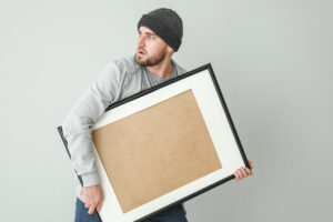Thief with picture stolen from art gallery on light background