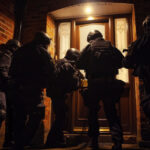 Five National Crime Agency officers in black uniforms are trying to break in a house which considered to be a crime scene in the middle of the night --ar 3:2 --style raw Job ID: 5cf273e0-fa40-43b8-bd10-a0715fa9a8f5